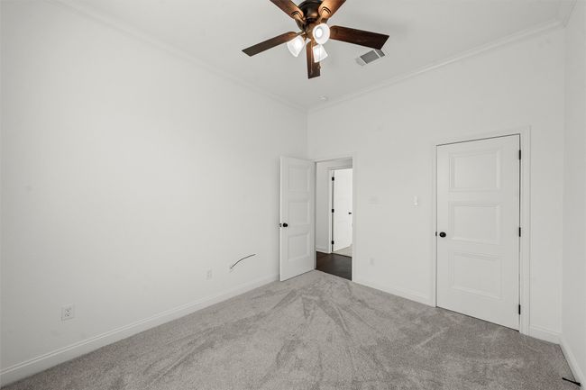Unfurnished bedroom with carpet, ornamental molding, and a ceiling fan | Image 23