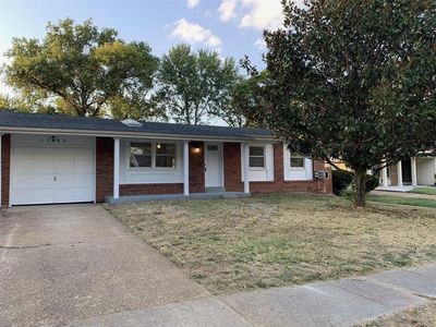 Ranch-style home featuring a front yard and a garage | Image 1