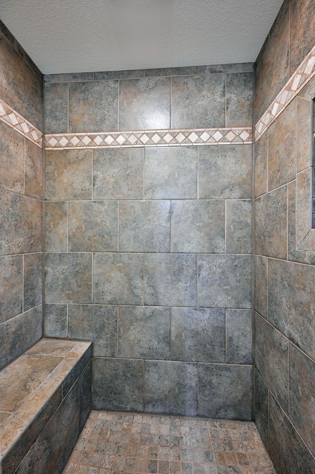 A close up view of the tile shower with a seat. | Image 42