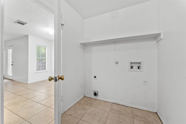 Laundry area with electric dryer hookup, washer hookup, light tile patterned floors, hookup for a gas dryer, and a textured ceiling | Image 19