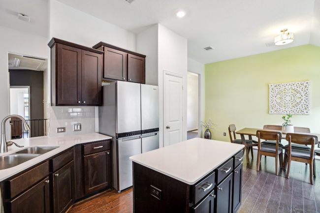Kitchen featuring a sink, dark wood finished floors, visible vents, freestanding refrigerator, and light countertops | Image 13