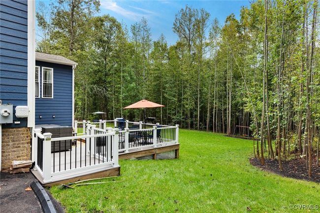 View of yard with outdoor dining area, a view of trees, and a wooden deck | Image 36