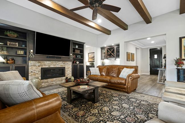 Living room featuring ceiling fan, wood finished floors, beam ceiling, baseboards, and a fireplace | Image 6