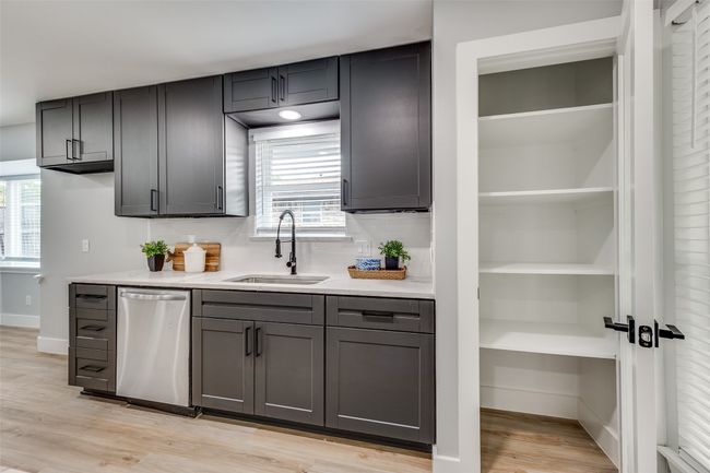Kitchen with stainless steel dishwasher, light countertops, light wood-style flooring, and decorative backsplash | Image 15