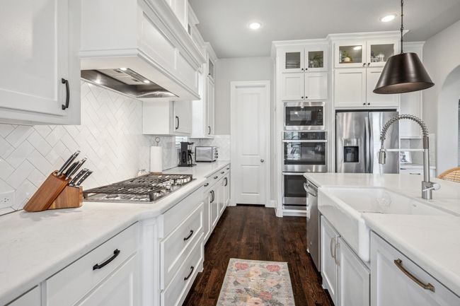 Kitchen with a sink, premium range hood, stainless steel appliances, white cabinets, and dark wood-type flooring | Image 4