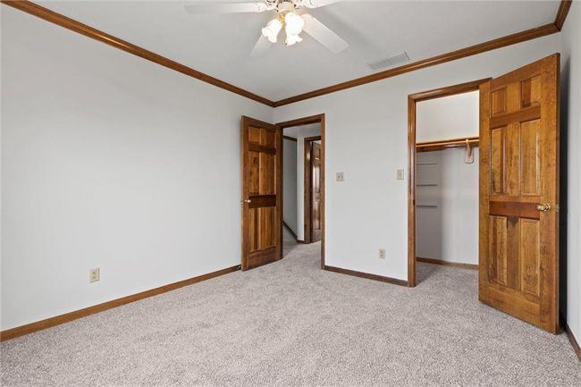 Unfurnished bedroom featuring ceiling fan, light colored carpet, crown molding, and a closet | Image 33