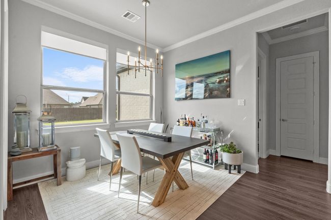 Dining area with wood finished floors, a chandelier, and crown molding | Image 9