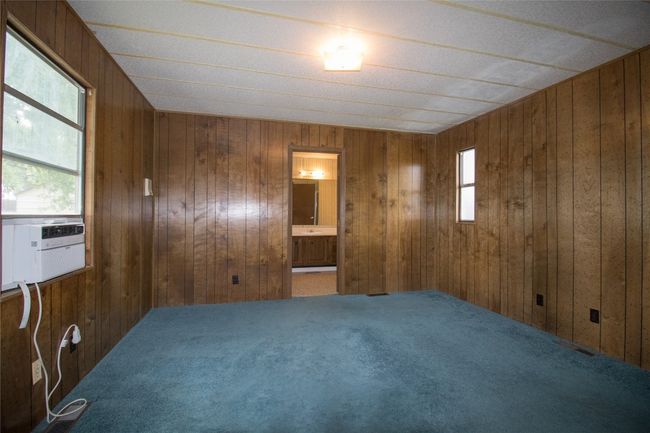 Carpeted empty room featuring wood walls and cooling unit | Image 5