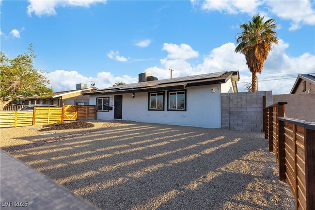 View of front of house featuring stucco siding, a gate, solar panels, and a fenced backyard | Image 44