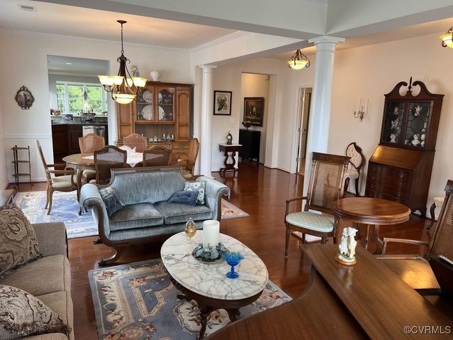 Living room with ornamental molding, decorative columns, a chandelier, and dark hardwood / wood-style flooring | Image 9