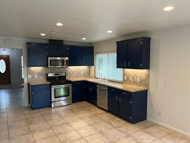 Kitchen featuring appliances with stainless steel finishes, backsplash, light tile patterned floors, recessed lighting, and light countertops | Image 7