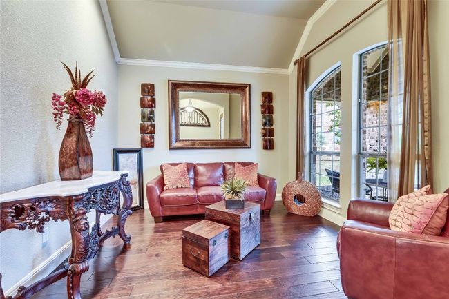 Living area with vaulted ceiling, wood-type flooring, crown molding, and a textured wall | Image 9