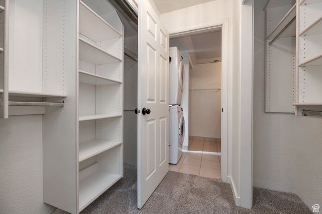 Walk in closet featuring stacked washer / dryer, tile patterned floors, and carpet flooring | Image 13