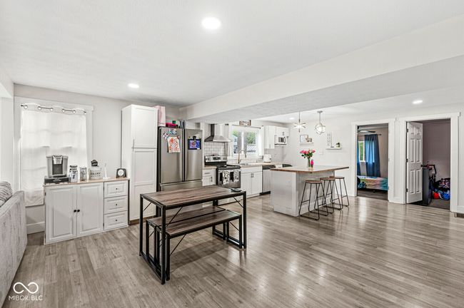 kitchen with stainless steel appliances, wall chimney range hood, light wood-style floors, white cabinets, and recessed lighting | Image 7
