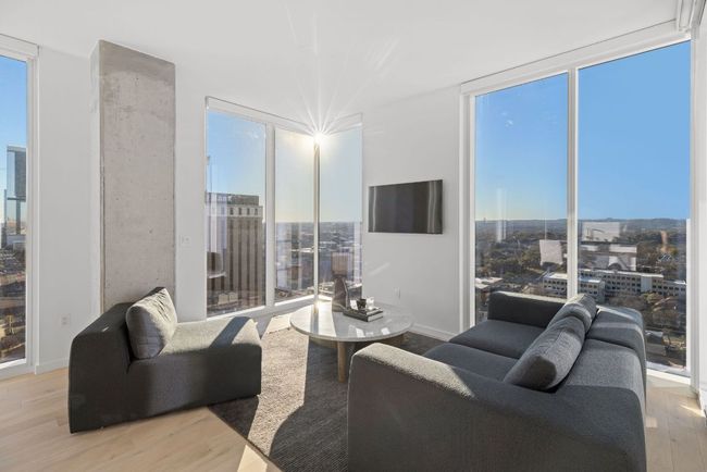 Living area with floor to ceiling windows, wood finished floors, baseboards, and a wealth of natural light | Image 7