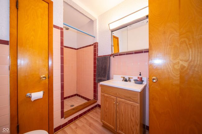 bathroom featuring a shower stall, vanity, wood finished floors, tile walls, and wainscoting | Image 13