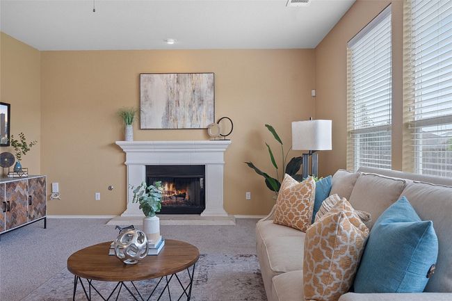 Carpeted living area featuring a warm lit fireplace and baseboards | Image 12