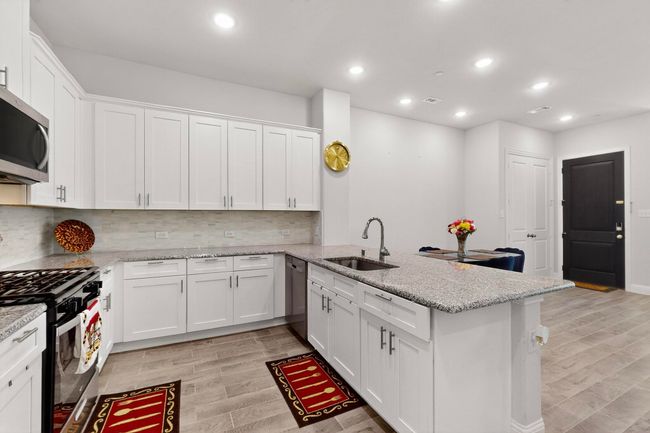 Kitchen featuring stainless steel appliances, a peninsula, white cabinets, recessed lighting, and light wood-type flooring | Image 9