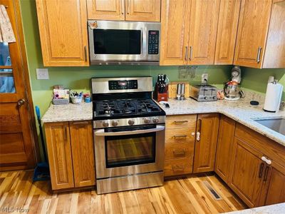 Kitchen with appliances with stainless steel finishes, light stone countertops, and light wood-type flooring | Image 2