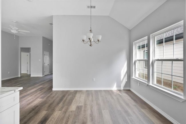 Unfurnished dining area with lofted ceiling, a chandelier, wood finished floors, and ceiling fan | Image 6