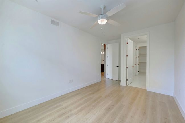 Empty room with light wood-style floors and a ceiling fan | Image 12