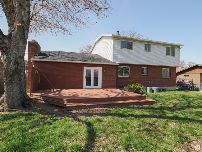 Rear view of property featuring a yard, a wooden deck, french doors, and brick siding | Image 15