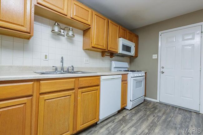 Kitchen featuring white appliances, backsplash, light countertops, and dark wood finished floors | Image 7