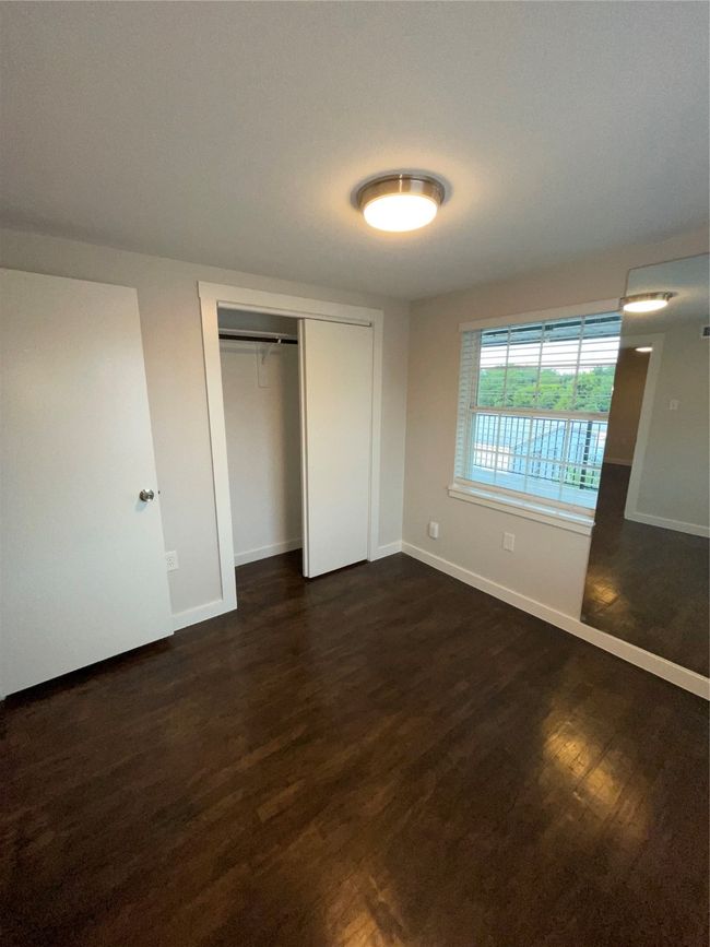 Unfurnished bedroom with baseboards, dark wood-style flooring, and a closet | Image 13