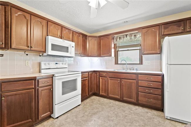 Kitchen featuring white appliances, a sink, light countertops, and ceiling fan | Image 13