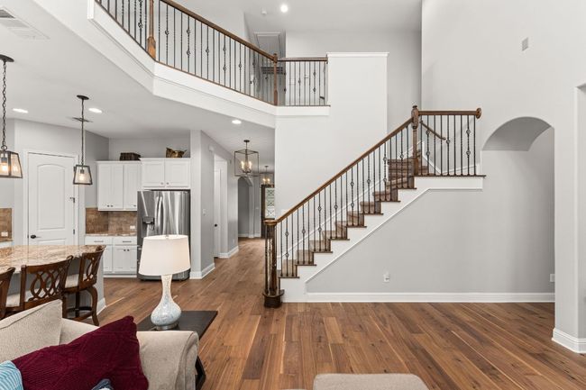 Living room with dark wood-style flooring, baseboards, visible vents, and stairway | Image 7