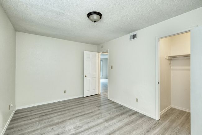 Unfurnished bedroom with light wood finished floors, a walk in closet, a textured ceiling, and a closet | Image 6
