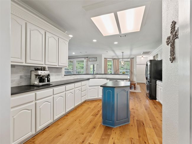 Kitchen featuring a peninsula, dark countertops, recessed lighting, ornamental molding, and light wood-style floors | Image 12