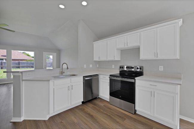 Kitchen with stainless steel appliances, a sink, a peninsula, vaulted ceiling, and white cabinets | Image 11