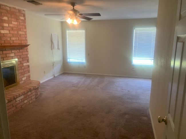 Unfurnished featuring carpet floors, healthy amount of natural light, a ceiling fan, and a fireplace | Image 9