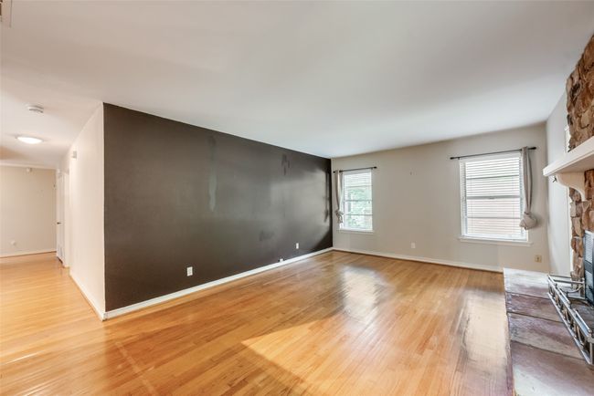 living room featuring a stone fireplace, baseboards, light wood-style floors, and visible vents | Image 5