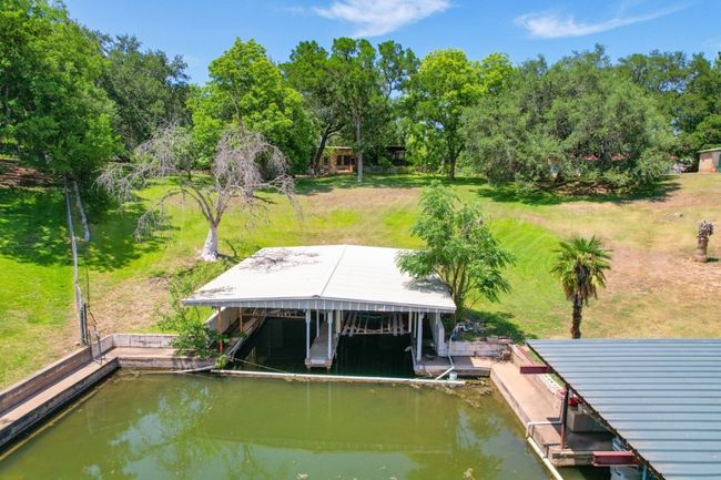 Dock with boat lift, a water view, view of scattered trees, and a lawn | Image 7