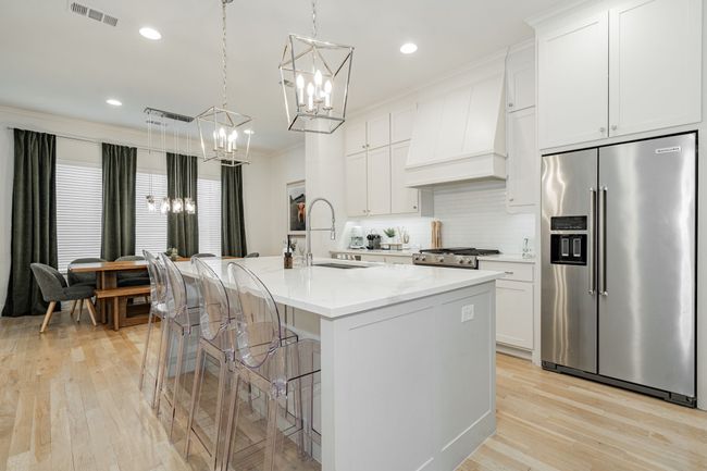 Kitchen featuring visible vents, a notable chandelier, premium range hood, high end refrigerator, and range | Image 9
