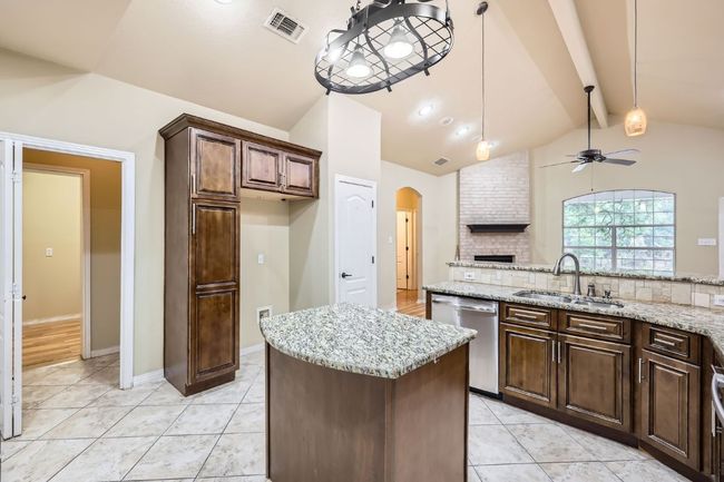 Kitchen featuring dishwasher, a sink, a ceiling fan, arched walkways, and a kitchen island | Image 8