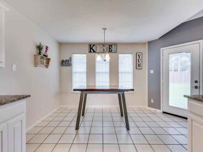 Unfurnished dining area with a chandelier, light tile patterned floors, and baseboards | Image 15
