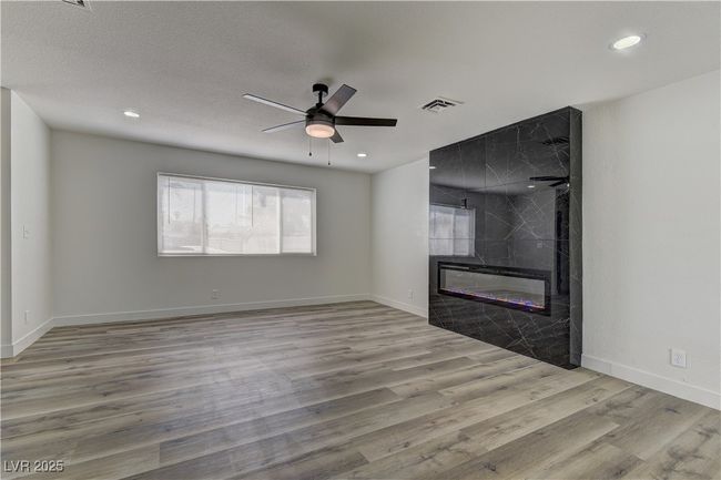 Unfurnished living room featuring wood finished floors, a ceiling fan, recessed lighting, a tile fireplace, and baseboards | Image 7