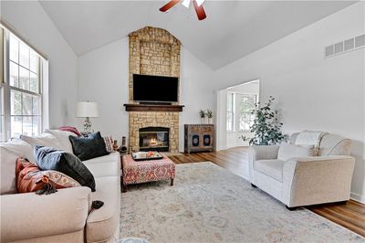 Living room featuring wood-type flooring, a fireplace, vaulted ceiling, and a wealth of natural light | Image 3