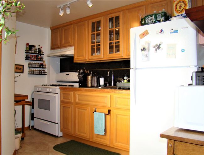 Kitchen with backsplash, white appliances, and light tile patterned floors | Image 17