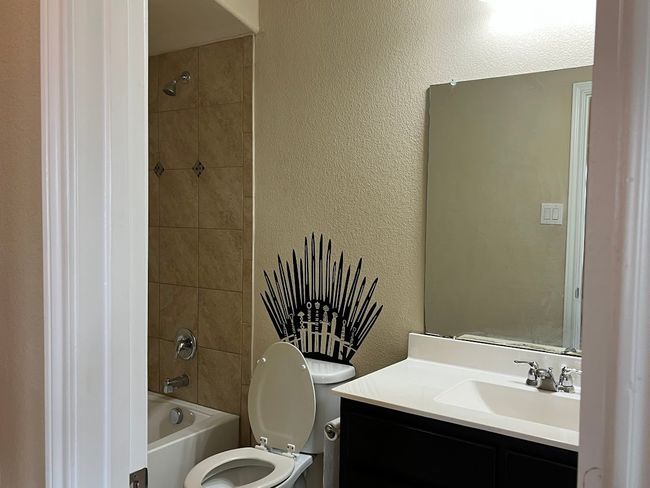Bathroom featuring a textured wall, toilet, vanity, and bathtub / shower combination | Image 15
