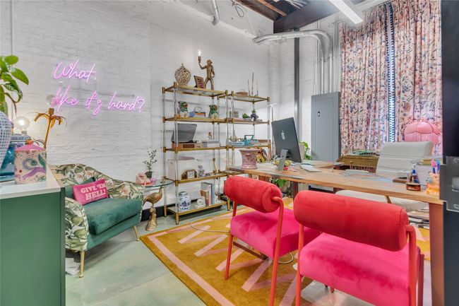 Office area featuring concrete flooring, a high ceiling, and brick wall | Image 12