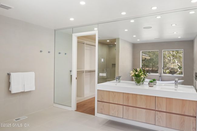 Stunning primary bathroom with wall of mirror, floating double sinks adjoins walk-in-closet | Image 28