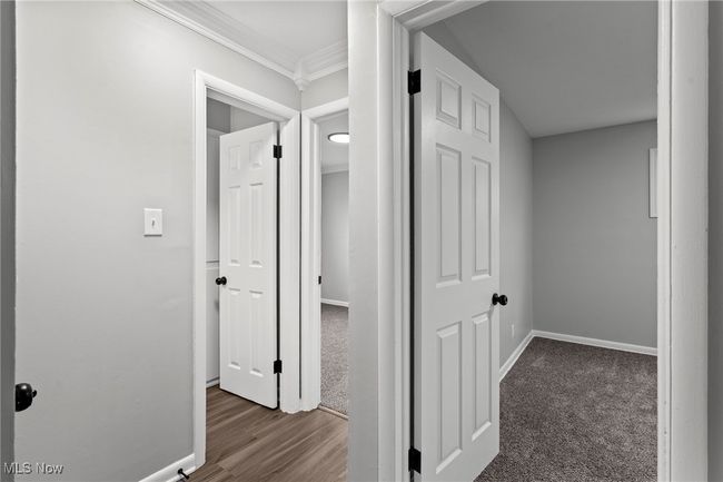 Corridor featuring carpet floors, wood finished floors, crown molding, and baseboards | Image 22