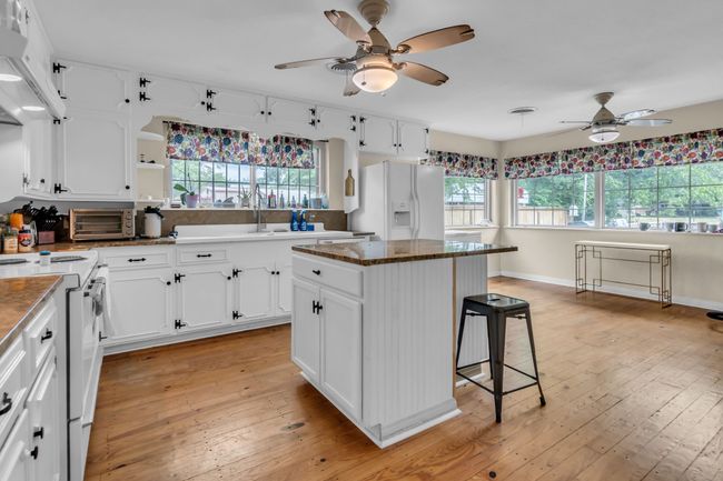 Kitchen featuring ceiling fan, white appliances, a kitchen breakfast bar, and plenty of natural light | Image 11
