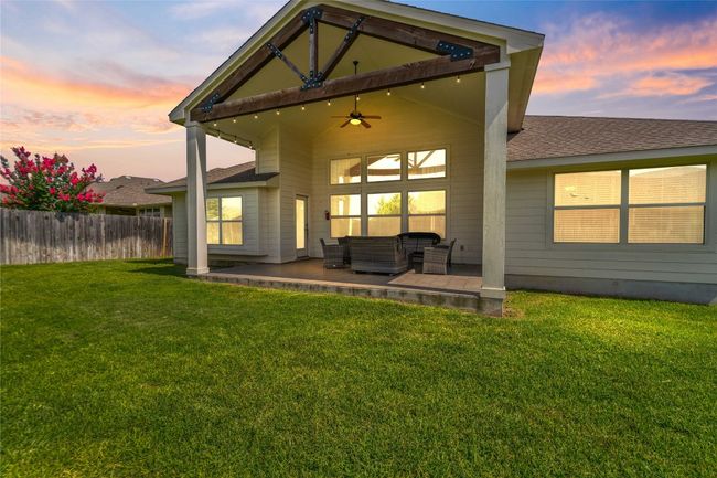 Back of house at dusk with an outdoor living space, ceiling fan, a shingled roof, and a patio | Image 25
