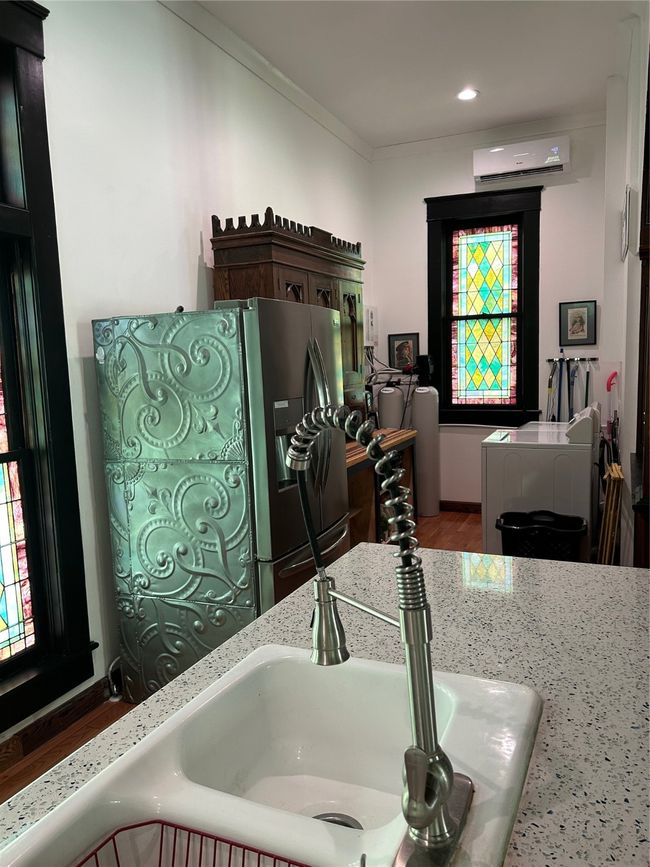Kitchen view of washer / clothes dryer, crown molding, stainless steel refrigerator with ice dispenser, and an AC wall unit | Image 5