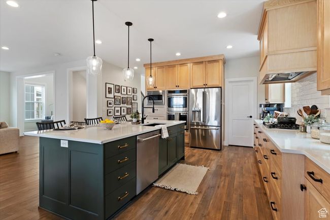 Kitchen with tasteful backsplash, light brown cabinetry, light countertops, appliances with stainless steel finishes, and dark wood-style floors | Image 12